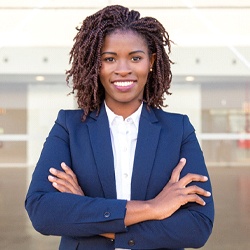 person in a business suit smiling with their arms crossed