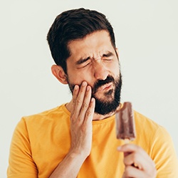 a person biting into a popsicle and experiencing tooth sensitivity