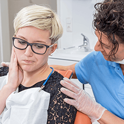 Young woman in pain holding cheek