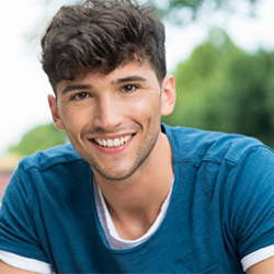 A young man smiling outside.