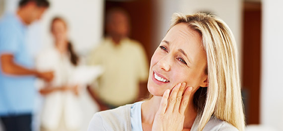 Woman grimacing and holding cheek