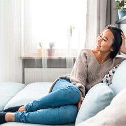 person smiling and sitting on their couch