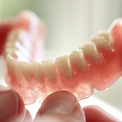 Hand holding a full denture