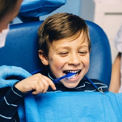 boy brushing teeth in dental chair
