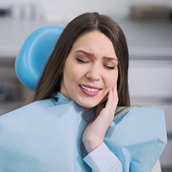 Woman in dental chair holding cheek