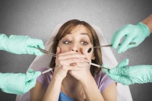 A dental patient anxiously covering her mouth