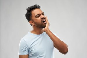 person holding their jaw because of a toothache