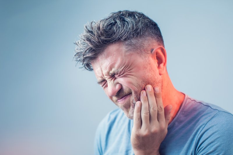 person with toothache holding cheek